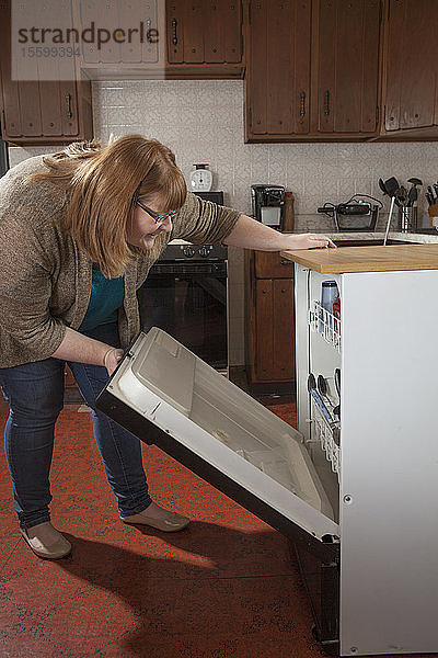 Eine blinde Frau belädt den Geschirrspüler in ihrer Küche