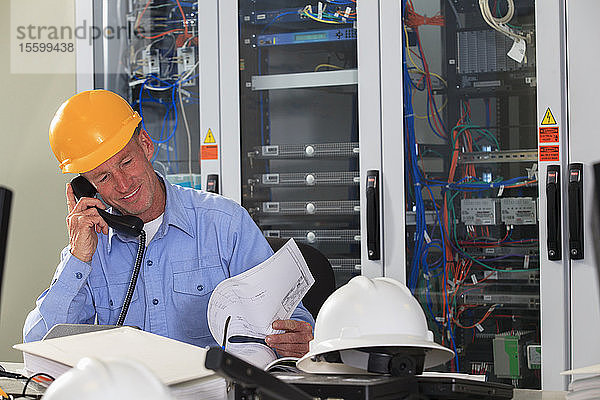 Elektroingenieur bei der Überprüfung von Prozessdiagrammen im Betriebsraum eines Elektrizitätswerks