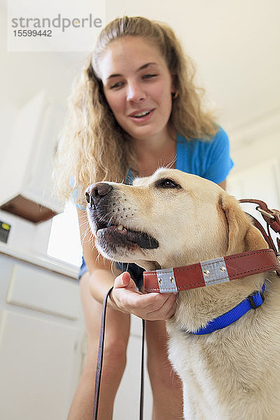 Frau mit Sehbehinderung legt ihrem Diensthund den Gurt an