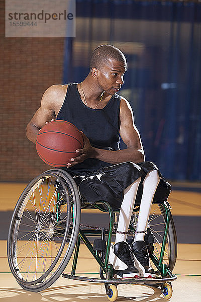 Mann mit Spinaler Meningitis sitzt im Rollstuhl und spielt Basketball