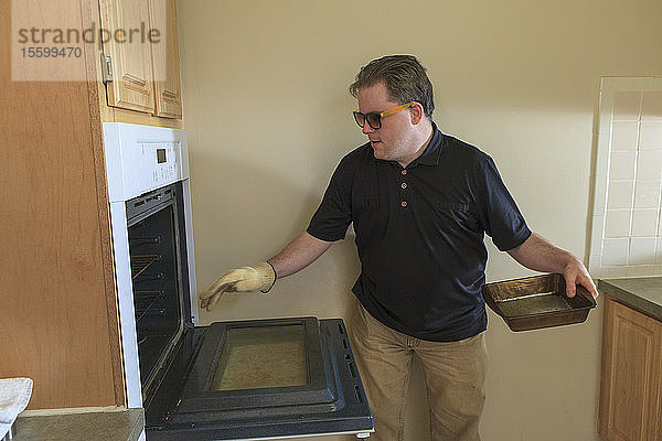 Mann mit angeborener Blindheit benutzt den Backofen in seiner Küche