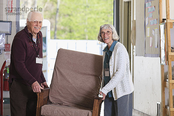 Älteres Ehepaar bewegt Möbel in einem Lagerhaus