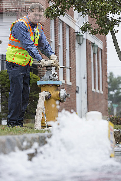 Ein Techniker der Wasserbehörde öffnet einen Hydranten  um die Wasserleitungen zu spülen
