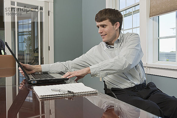 Geschäftsmann mit Querschnittslähmung  der in einem Büro einen Laptop benutzt