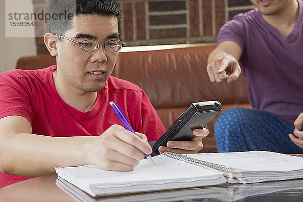 Asiatischer Mann mit Autismus arbeitet mit seinem Bruder an seinen Hausaufgaben