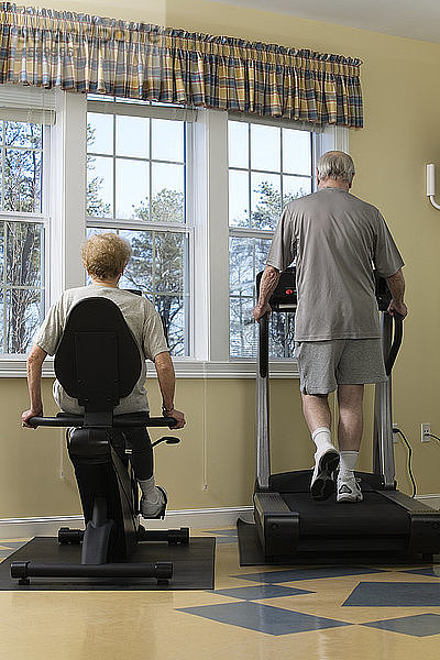 Ein älteres Paar trainiert im Fitnessstudio.