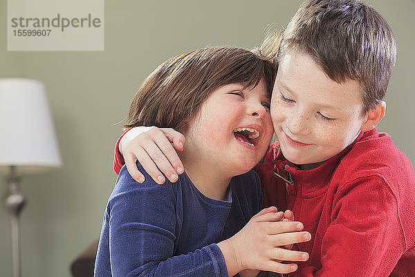 Kleines Mädchen mit Down-Syndrom lacht mit ihrem Bruder