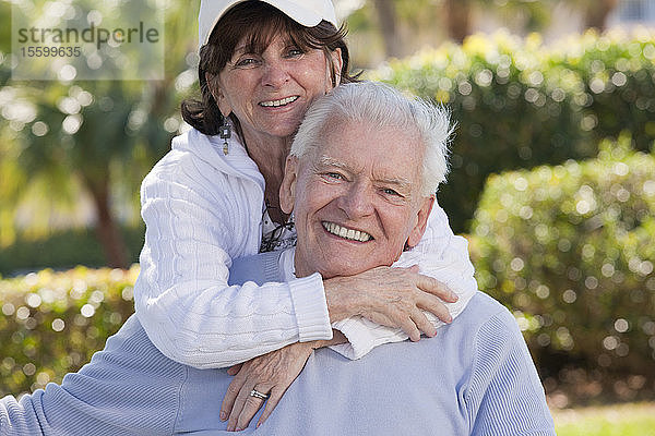 Porträt einer älteren Frau  die einen älteren Mann von hinten umarmt
