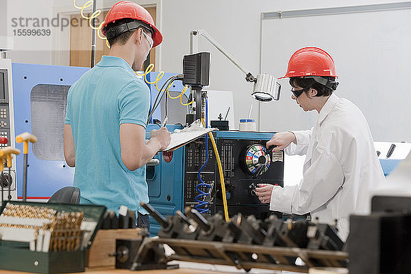 Assistent und Ingenieurstudent bei der Bedienung der CNC-Maschine