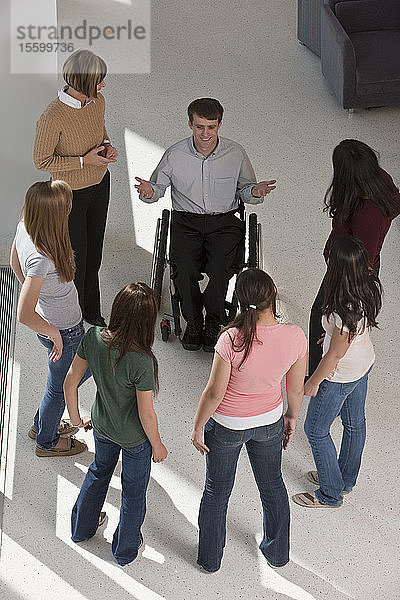 Rückenmarkverletzte Lehrerin im Rollstuhl mit Schülern und ihren Müttern