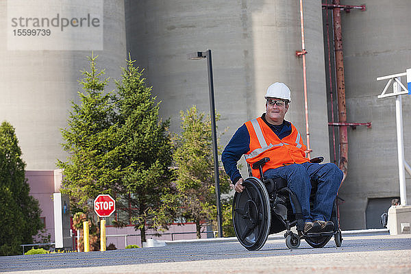 Techniker im Rollstuhl bei der Inspektion von Lagertanks im Freien