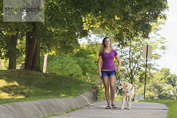 Frau mit Sehbehinderung geht mit ihrem Diensthund spazieren