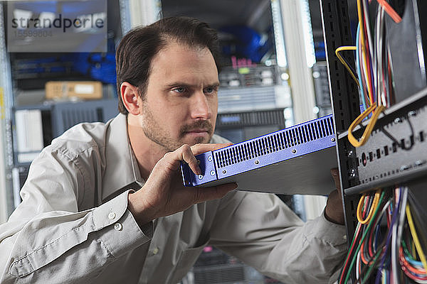 Netzwerktechniker bei der Installation eines Switches im Rechenzentrum