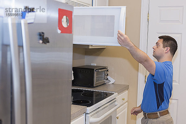 Mann mit Down-Syndrom öffnet Schublade in der Küche