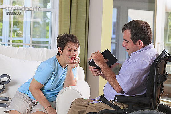Ehepaar mit Cerebralparese schaut auf ein digitales Tablet