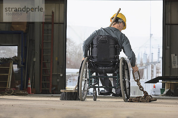 Instandhaltungsleiter mit Rückenmarksverletzung bewegt Abschleppkette in Garage für Versorgungsfahrzeuge