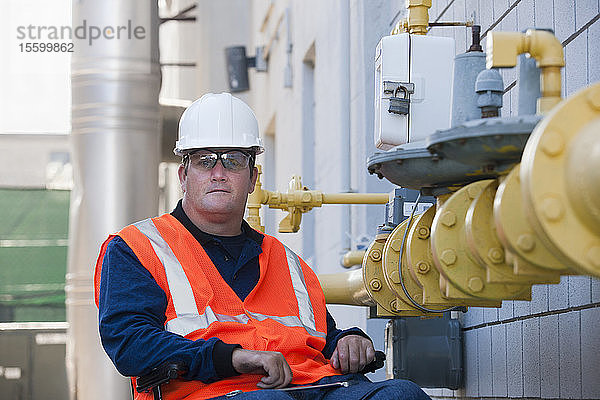 Gebäudetechniker im Rollstuhl bei der Inspektion einer Gasleitung