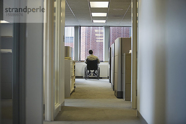 Rückansicht eines im Rollstuhl sitzenden Mannes in einem Büro