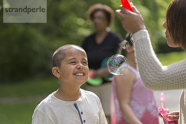 Hispanischer Junge mit Autismus spielt draußen mit seiner Familie