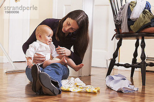 Mutter  die ihrem Sohn die Kleidung wechselt  während sie auf dem Boden sitzt