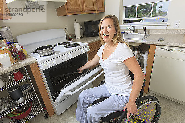 Frau mit Querschnittslähmung in ihrer barrierefreien Küche  die einen Herd benutzt