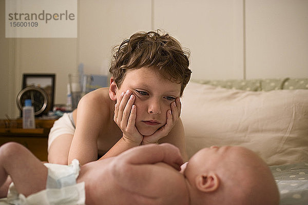 Blick auf einen kleinen Jungen  der ein Baby betrachtet