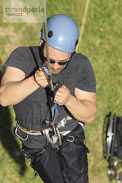 Mann mit Querschnittslähmung benutzt adaptive Kletterausrüstung zum Klettern
