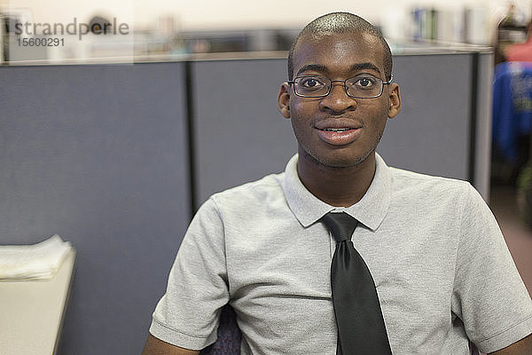 Porträt eines afroamerikanischen Mannes mit Autismus  der in einem Büro arbeitet