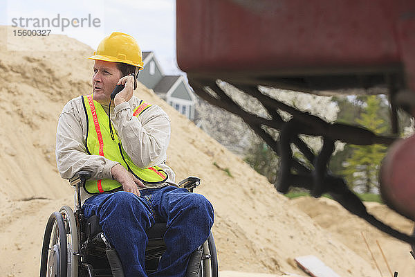 Bauleiter mit Querschnittslähmung am Walkie Talkie auf der Baustelle