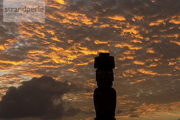 Ein einzelner Moai hebt sich als Silhouette vom leuchtend roten Sonnenuntergangshimmel ab; Osterinsel  Chile