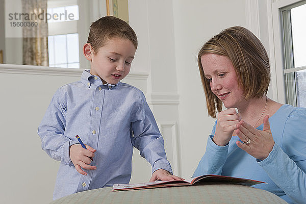Frau gebärdet das Wort Draw in amerikanischer Zeichensprache  während sie ihren Sohn unterrichtet