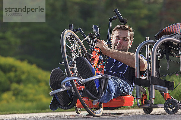 Ein Mann mit einer Rückenmarksverletzung stellt seine Füße auf seinem speziell angefertigten Handbike ein