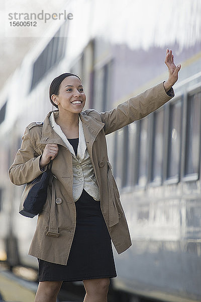 Hispanische Frau winkt zum Abschied auf einem Bahnsteig