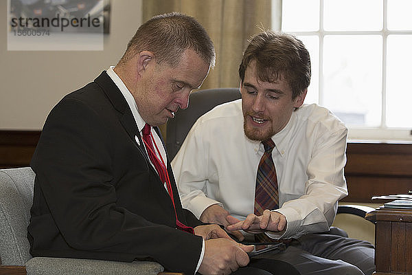 Ein Mann mit Down-Syndrom  der als Assistent der Legislative arbeitet  benutzt ein Tablet mit seinem Kollegen im Büro im State Capitol