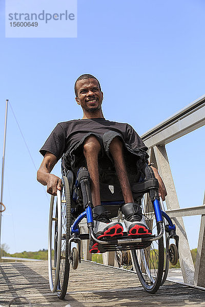 Mann im Rollstuhl  der an Spinaler Meningitis erkrankt war  fährt eine Rampe hinunter zu einem Dock