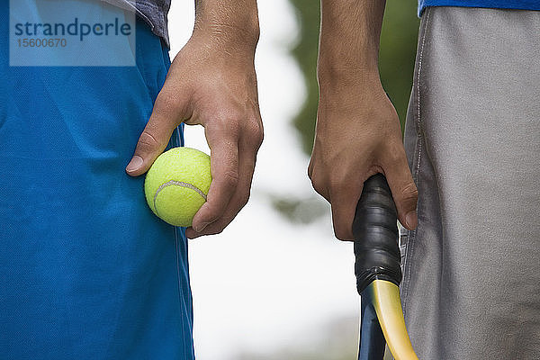 Halbansicht von zwei Teenagern  die einen Tennisball und einen Tennisschläger halten