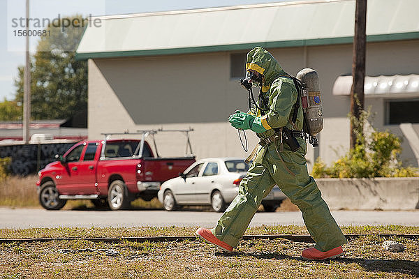 HazMat-Feuerwehrmann geht mit einer Kamera durch ein Feld