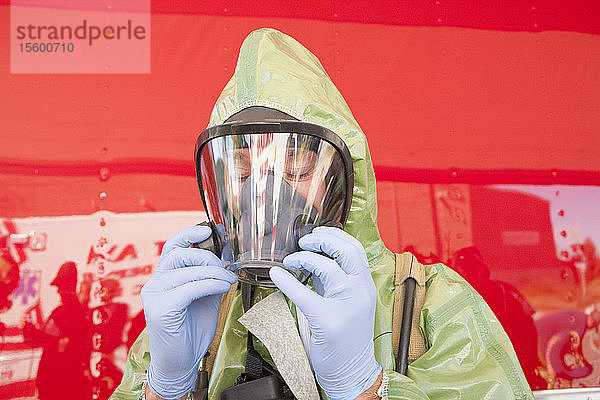 Nahaufnahme eines HazMat-Feuerwehrmanns beim Anlegen der Maske