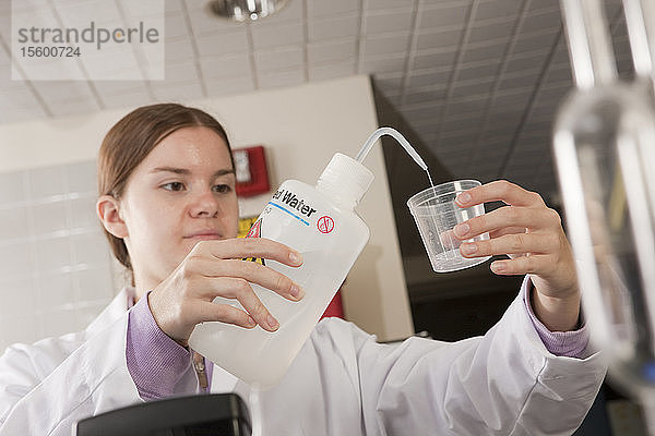 Wissenschaftler  der destilliertes Wasser in einen Probenbehälter im Labor einfüllt