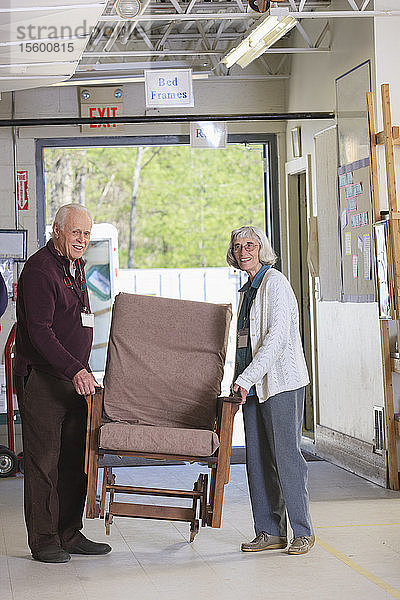Älteres Ehepaar bewegt Möbel in einem Lagerhaus