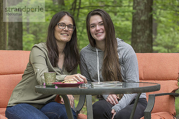 Glückliche Frau mit Multipler Sklerose sitzt mit ihrer Tochter zusammen