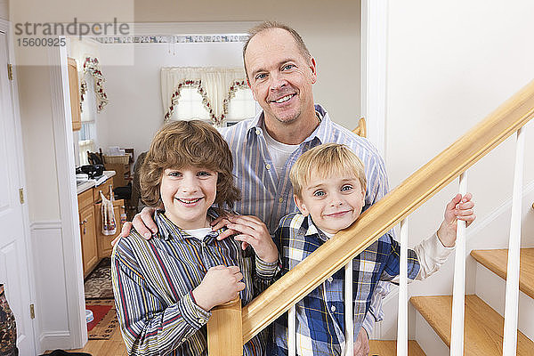 Porträt eines glücklichen Mannes mit seinen beiden Söhnen zu Hause