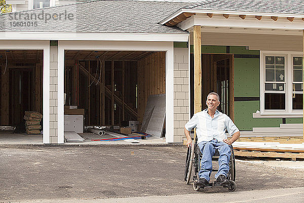 Ein querschnittsgelähmter Mann im Rollstuhl in seinem neuen  im Bau befindlichen barrierefreien Haus