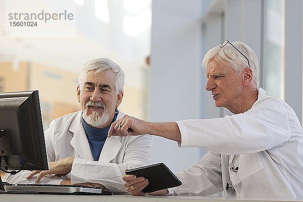 Zwei Ärzte besprechen Informationen auf einem Computer und einem Tablet  einer mit Muskeldystrophie