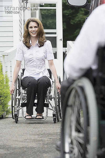Mittlere erwachsene Frau mit einer Rückenmarksverletzung sitzt im Rollstuhl und lächelt