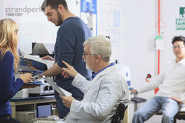 Professor mit Muskeldystrophie und Studenten der Ingenieurswissenschaften verwenden Anleitung zum Aufbau eines Röntgenfluoreszenzexperiments in einem Labor