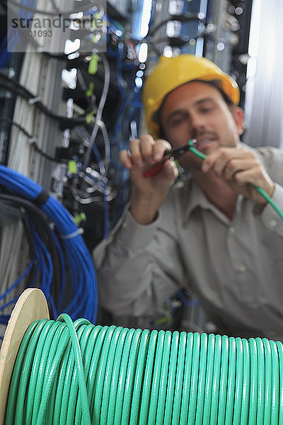 Netzwerktechniker beim Schneiden von Kabelanschlüssen im Netzwerkrechenzentrum