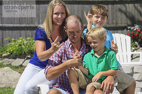 Porträt einer glücklichen Familie mit Hörbehinderung  die Ich liebe dich in amerikanischer Zeichensprache gebärdet