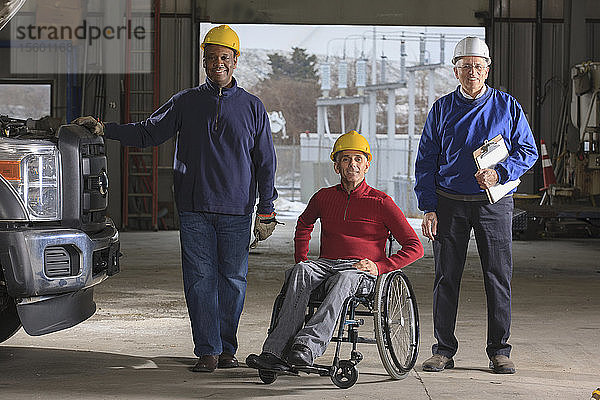 Ingenieure  einer mit Rückenmarksverletzung  und Betreuer in der Garage des Elektrizitätswerks