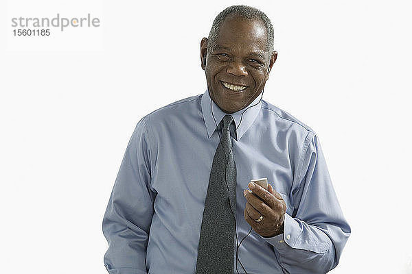 Porträt eines Geschäftsmannes  der einen iPod hört und lächelt